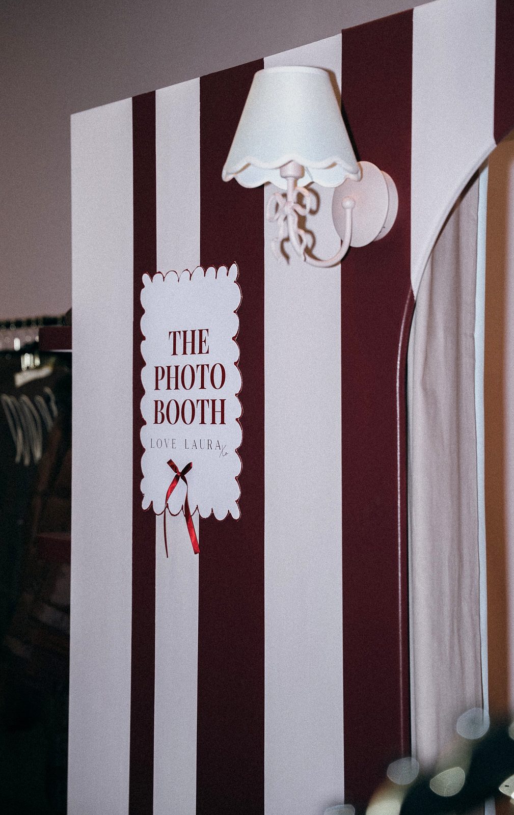 Love Laura photo booth with burgundy and white striped walls, a scalloped sign reading The Photo Booth and a white wall lamp